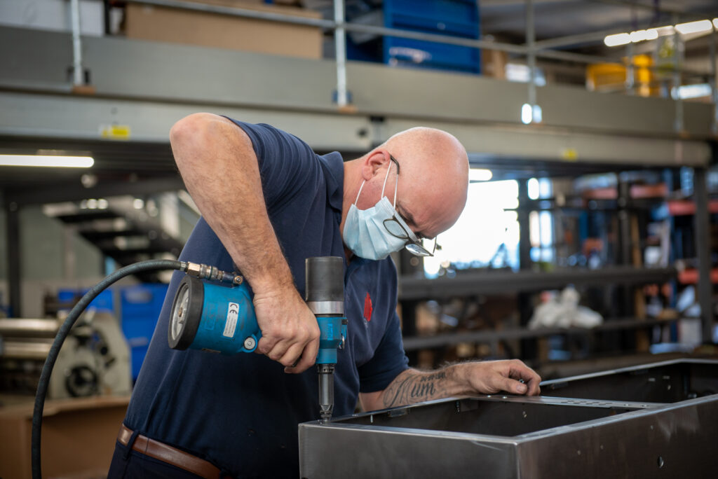 Man drilling sheet metal in factory