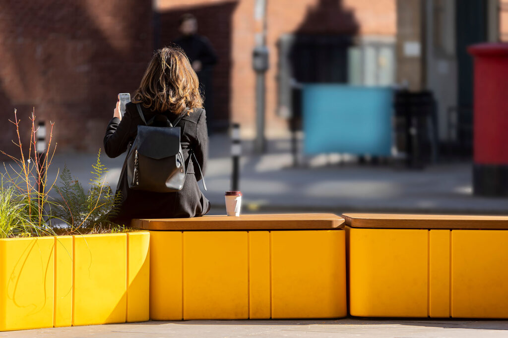 Woman having a coffee on Uniun bench outside Ikea Hammersmith